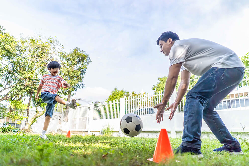 little boy playing football with father