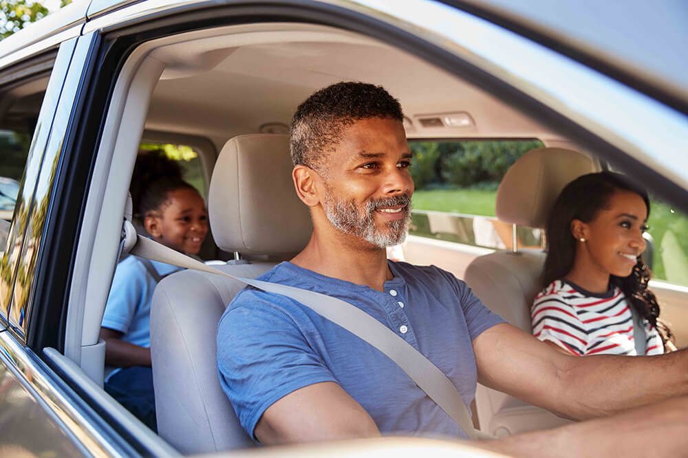 father driving car with family